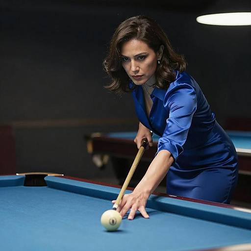 Photograph of a determined woman with dark hair in a blue satin blouse, leaning over a pool table, aiming to strike a ball with a cue stick