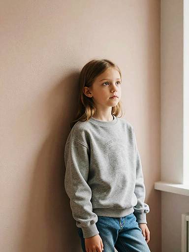Curious Girl Standing Indoors in Grey Sweatshirt