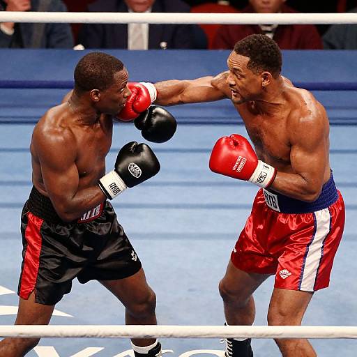 Photograph of intense boxing match: muscular Black boxer in black shorts vs. muscular Black boxer in red shorts, both punching gloves raised, in blue boxing