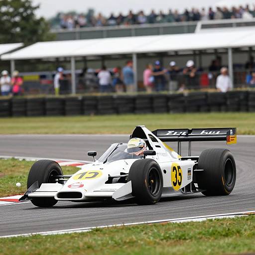 Photograph of a white Formula 1 car with black and yellow accents, number 35, racing on a track with blurred spectators in the background.