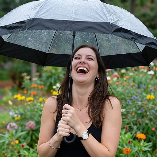 Photograph of a smiling woman with long brown hair, holding a black-and-white umbrella, wearing a black sleeveless top, standing in a colorful,