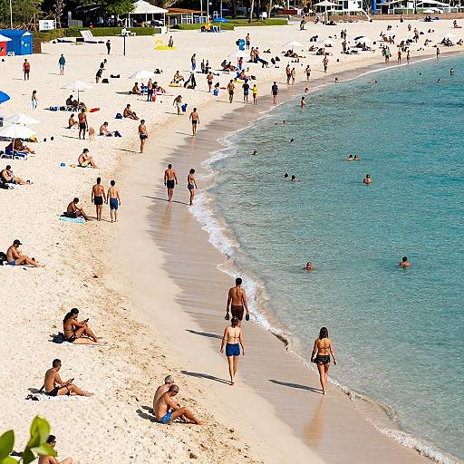 Photograph of a bustling, sunlit beach with numerous sunbathers, swimmers, and beachgoers wearing swimsuits, against turquoise waters and