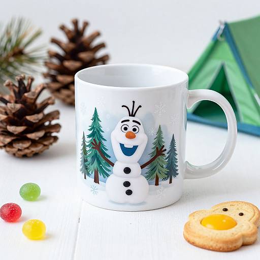 Photograph of a white ceramic mug with a colorful snowman and pine trees design, featuring pine cones, a green tent, and Christmas lights, with