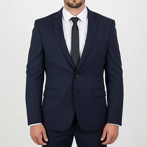Photograph of a man in a black suit, white shirt, and black tie, centered against a plain white background.