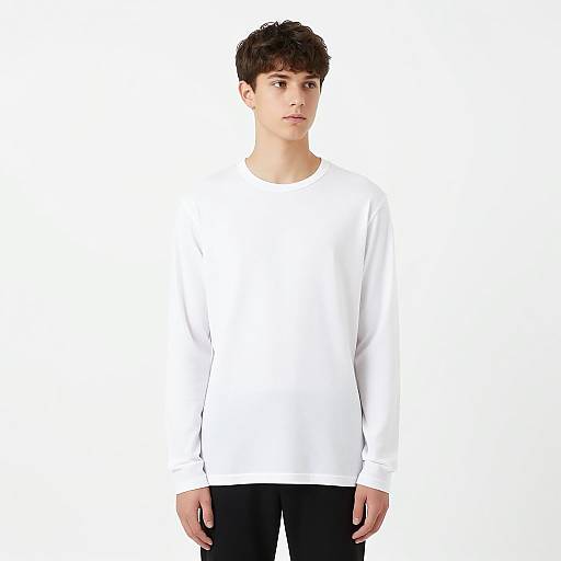 Photograph of a young man with short, dark brown hair, wearing a plain white long-sleeve shirt and black pants, standing against a white