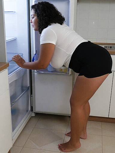 Curly-Haired Woman Reaching Into Fridge