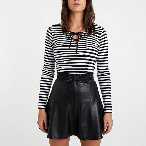 Photograph of a woman wearing a black-and-white striped long-sleeve top with a lace-up front, and a black leather skirt with a high