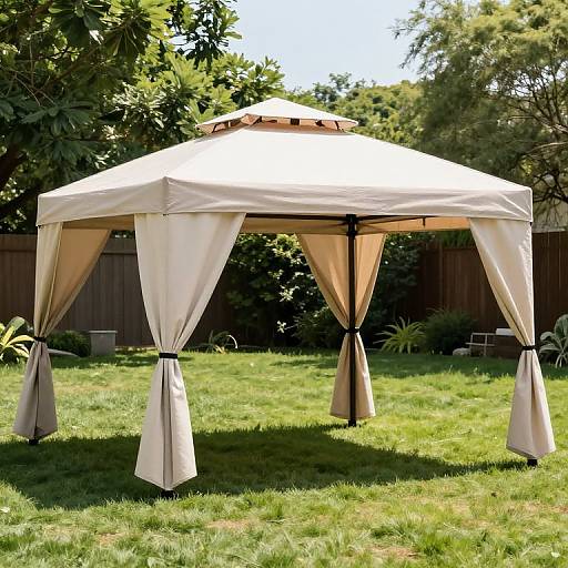Photograph of a beige, octagonal outdoor gazebo with draped curtains on a sunny green lawn, surrounded by trees and a wooden fence.