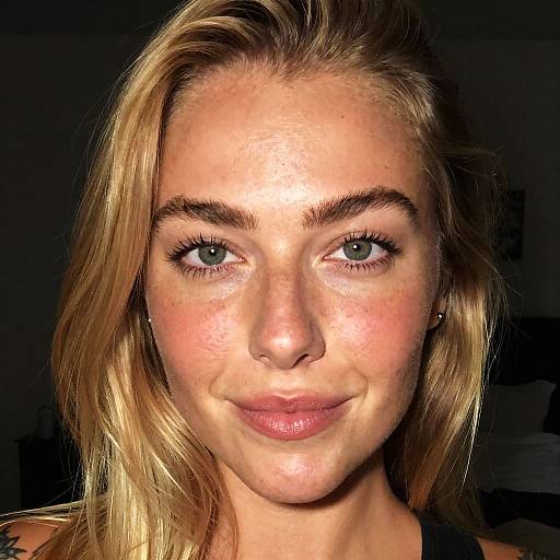 Close-up Portrait of Smiling Blonde Woman in Dark Room