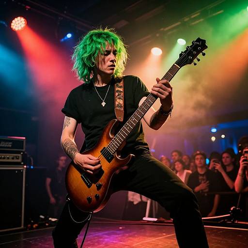 Photograph of a green-haired, tattooed rock musician playing a sunburst guitar on a vividly lit stage, with colorful spotlights and an engaged