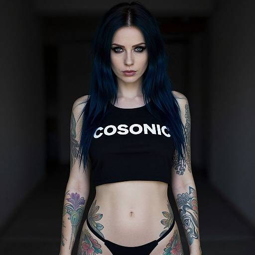 Photograph of a pale-skinned, black-haired woman with tattoos, wearing a black 