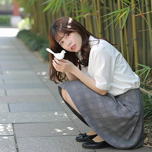 Asian Woman Holding White Bird Figurine Outdoors