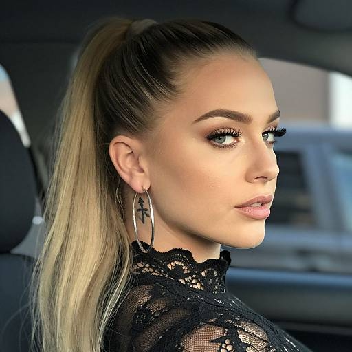 Photograph of a blonde woman with a high ponytail, wearing black lace top, hoop earrings, and dramatic eyeliner, looking over her shoulder inside