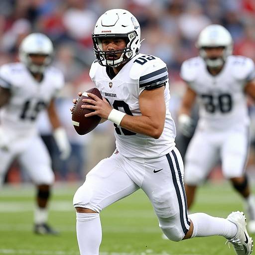Photograph of a muscular male football player in white uniform with black stripes, helmet, and number 4, running with a football, blurred teammates in