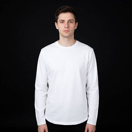 Photograph of a young man with short dark hair, fair skin, wearing a plain white long-sleeve shirt, standing against a solid black background