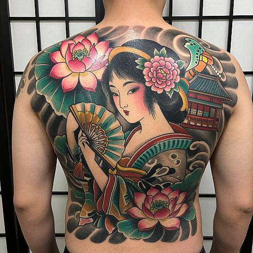 Tattooed Asian woman's back: traditional-style portrait with pink lotus, green leaves, folding fan, bird, and Japanese house on waves