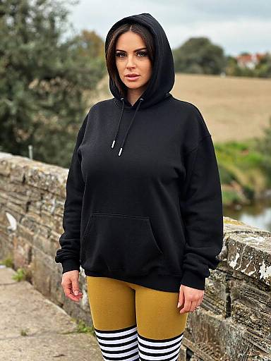 Photograph of a young woman with light brown skin and black hair, wearing a black hoodie, mustard-yellow leggings, and black-and-white striped socks,