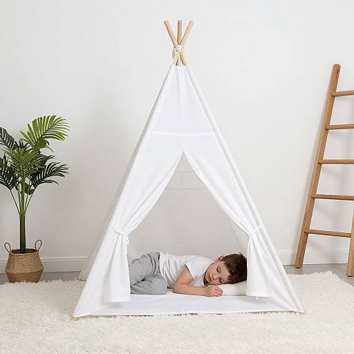 Photograph of a young child with brown hair lying inside a white, triangular canvas tent on a white carpet, with a wooden ladder and potted plant