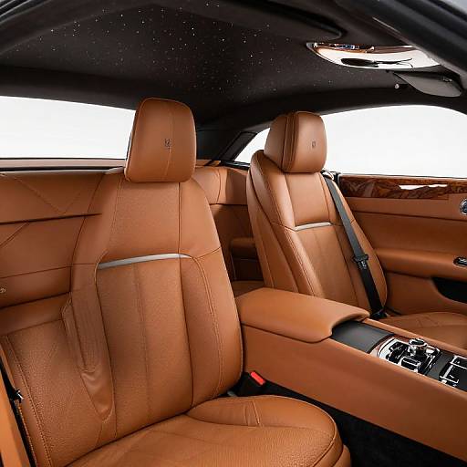 Photograph of a luxury car interior featuring rich, tan leather seats with stitched detailing, black headliner, and silver seat belts.