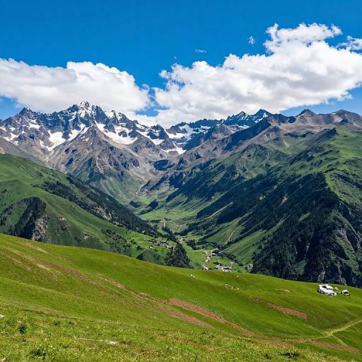 Photograph of a vibrant mountain landscape with green grassy hills, snow-capped peaks, scattered white houses, and a bright blue sky with fluffy clouds