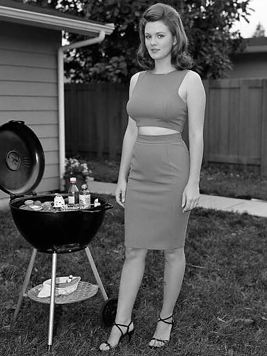 Black-and-white photograph of a fair-skinned woman with short, wavy hair, wearing a sleeveless, form-fitting knee-length dress and black