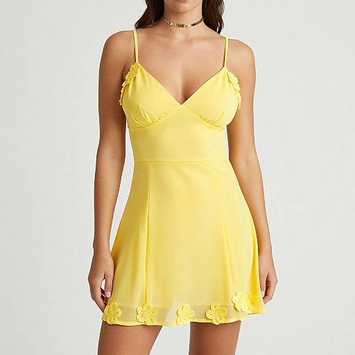 Photograph of a woman in a yellow, V-neck, floral-embellished mini dress with thin straps and a gold choker necklace.