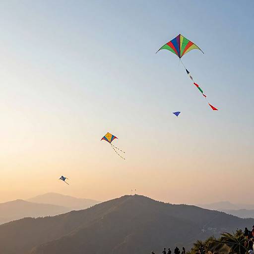 Photograph of colorful kites flying over a hilly landscape at sunset, with a clear sky transitioning from blue to orange.