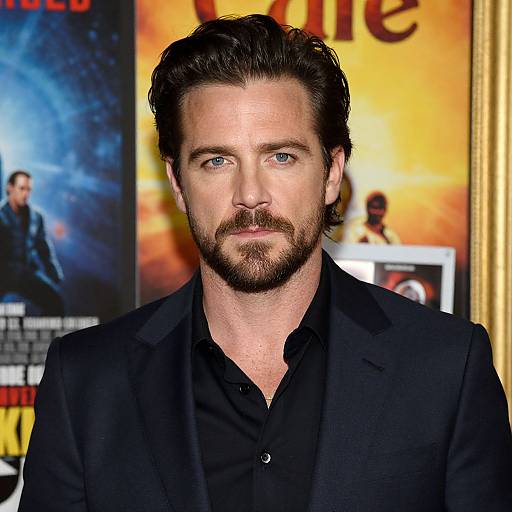 Photograph of Matthew McConaughey with blue eyes, dark hair, and beard, wearing a black shirt and blazer, in front of movie