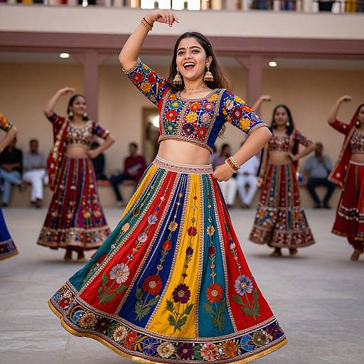 Photograph of a smiling Indian woman in a colorful traditional lehenga, performing a dance with other women in a courtyard.