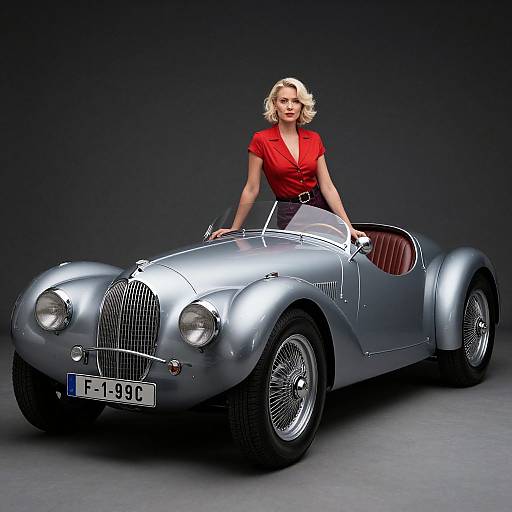 Photograph of a blonde woman in a red blouse and black skirt, leaning on a sleek, silver vintage convertible car.