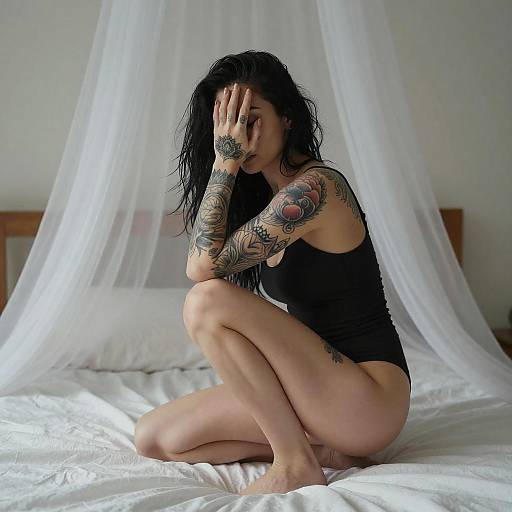 Tattooed Woman Crouching on Bed