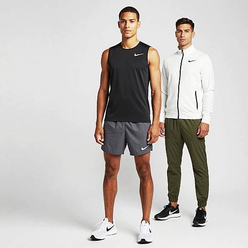 Photograph of two athletic men: one in black Nike tank top and gray shorts, the other in white Nike jacket and green pants. Both standing against