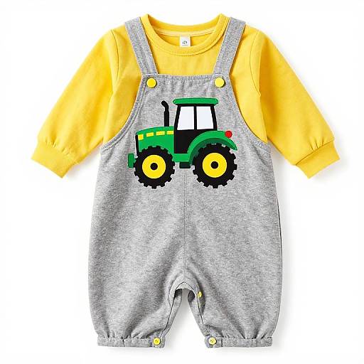 Photograph of a gray baby overall with a green tractor graphic, yellow shirt, and yellow snap buttons, laid flat.