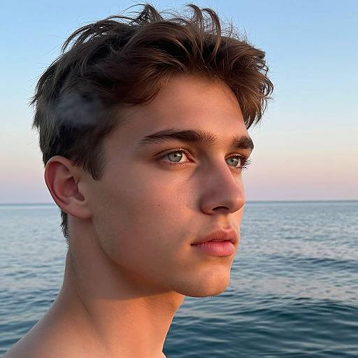 Photograph of a young, handsome man with short, dark brown hair, blue eyes, and fair skin, looking to the side against a serene ocean