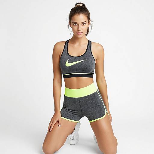 Photograph of a fit, fair-skinned woman with dark hair in a ponytail, wearing a black Nike sports bra, yellow Nike shorts, and