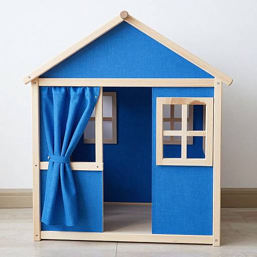 Photograph of a wooden playhouse with blue walls, light wooden frame, blue curtain on left, and small window on right.