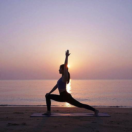Silhouetted man in yoga pose on beach at sunset, arms raised, sun reflecting on calm ocean, pastel sky. Photograph.