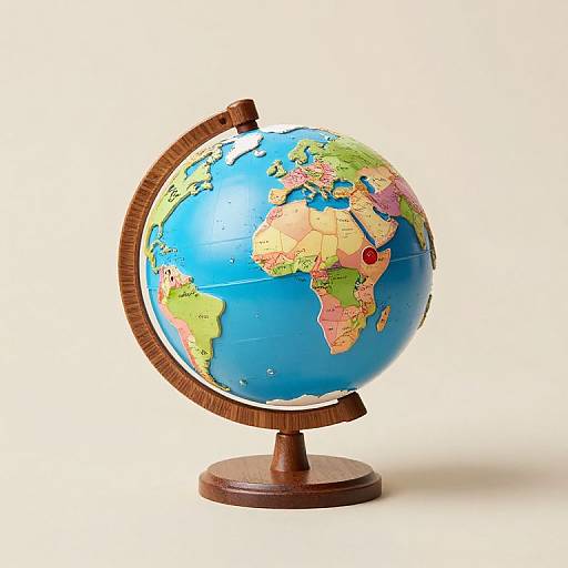 Photograph of a colorful, detailed, wooden globe with a red marker on Africa, standing on a round wooden base.