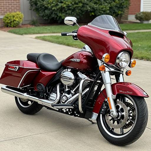 Photograph of a shiny, maroon Harley-Davidson touring motorcycle with black leather seat, chrome accents, and dual headlights, parked on a suburban
