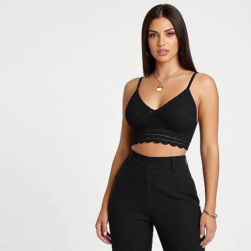 Photograph of a confident woman with long black hair, wearing a black crocheted crop top and high-waisted black pants, accessorized with