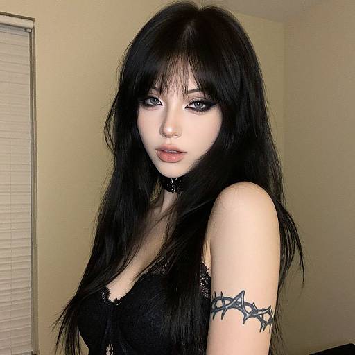 Photograph of a pale-skinned, black-haired woman with gothic makeup, black lace top, spiked arm tattoo, and black choker, standing