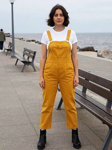 Woman in Mustard Yellow Overalls on Seafront Promenade