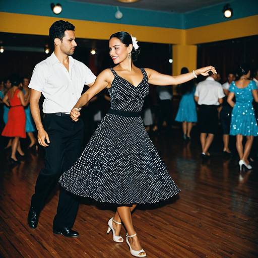 Photograph of a dancing couple in a vibrant ballroom; woman in black polka dot dress and white heels, man in white shirt and black pants