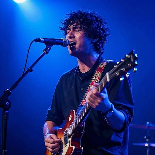 Male Musician Performing with Electric Guitar Under Blue Stage Light