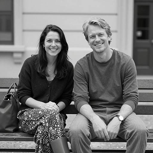 Smiling couple sitting on bench in black and white
