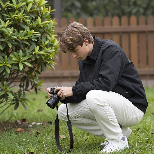 Crouching Young Man with Camera Outdoors
