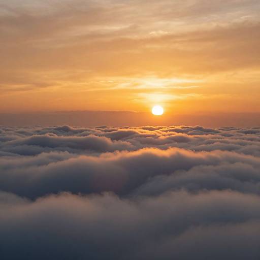 Photograph of a vibrant sunset over a sea of fluffy, illuminated clouds with warm orange and yellow hues in the sky.