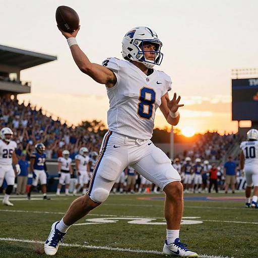 Photograph of a muscular male quarterback in white uniform with blue number 8, mid-throw, at sunset in a packed stadium.