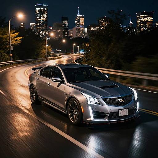 Photograph of a sleek, silver sedan with bright headlights speeding on a wet, curved highway at night, illuminated city skyline in the background.