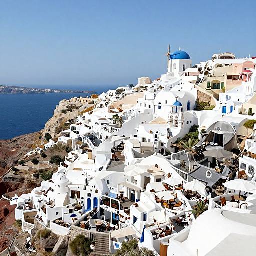 Photograph of a sunlit, white-washed Greek island village with blue domes, bright blue sky, and a deep blue sea in the background